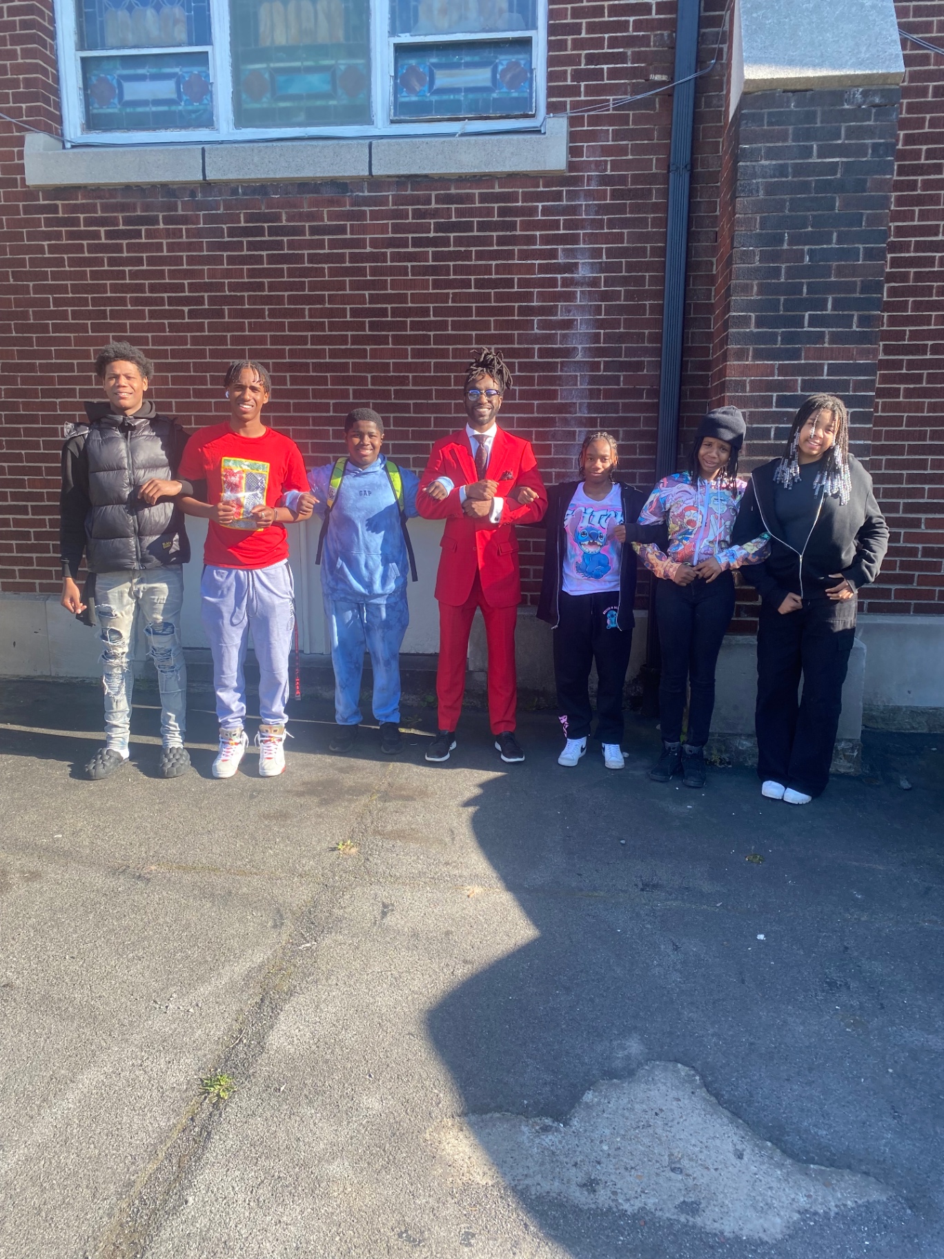Students linking arms in unity outside a community building
